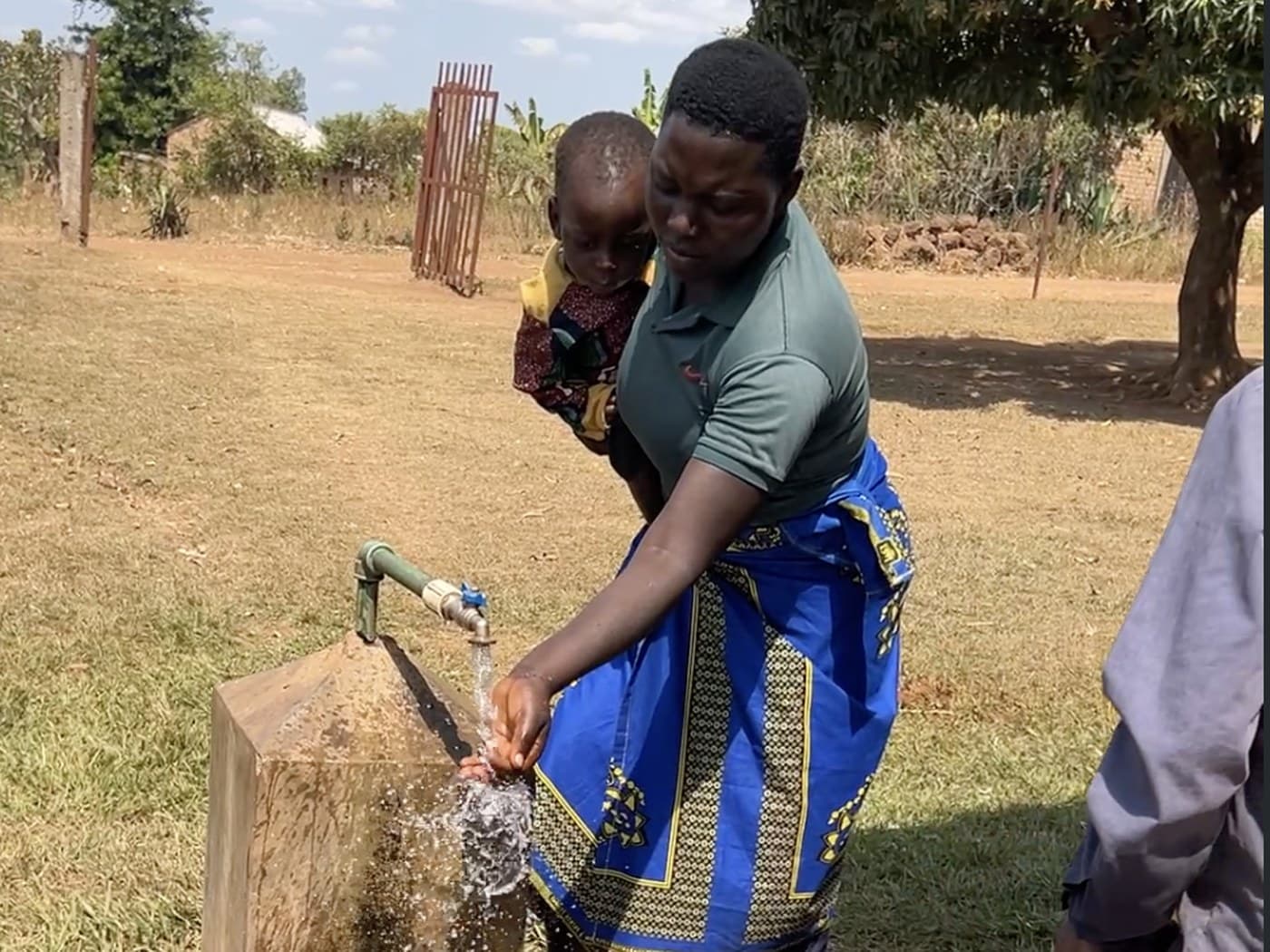 Una madre recoge agua potable del pozo de Ngomante con su hijo a la espalda